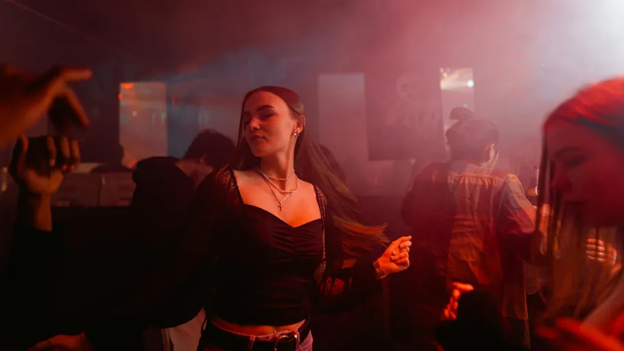 Woman dancing in dimly lit nightclub.