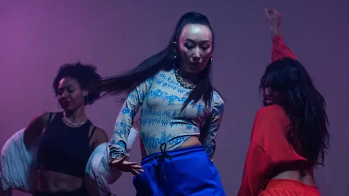 Three dancers performing in a dimly lit room.