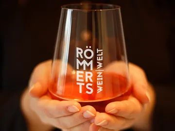 Transparentes Glas hält einen rosafarbenen Drink in den Händen.