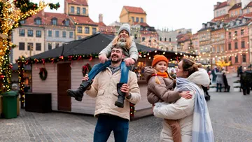 Familie genießt Weihnachtsmarkt, lächelt, Winterkleidung.