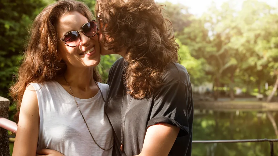 Couple embracing near a park lake.