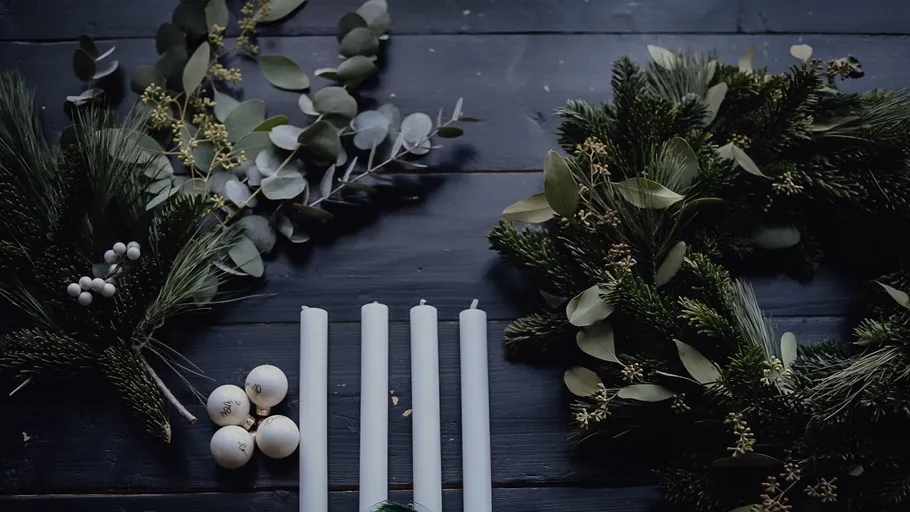 Candles and wreaths on dark wooden table.