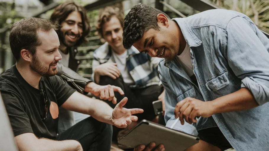 Group of friends looking at a tablet outdoors.