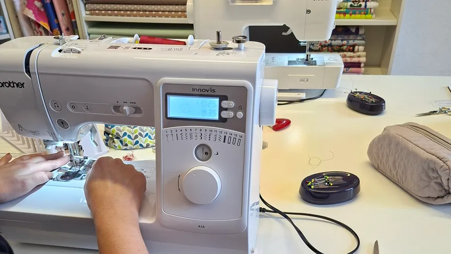 Person näht mit einer weißen Nähmaschine.