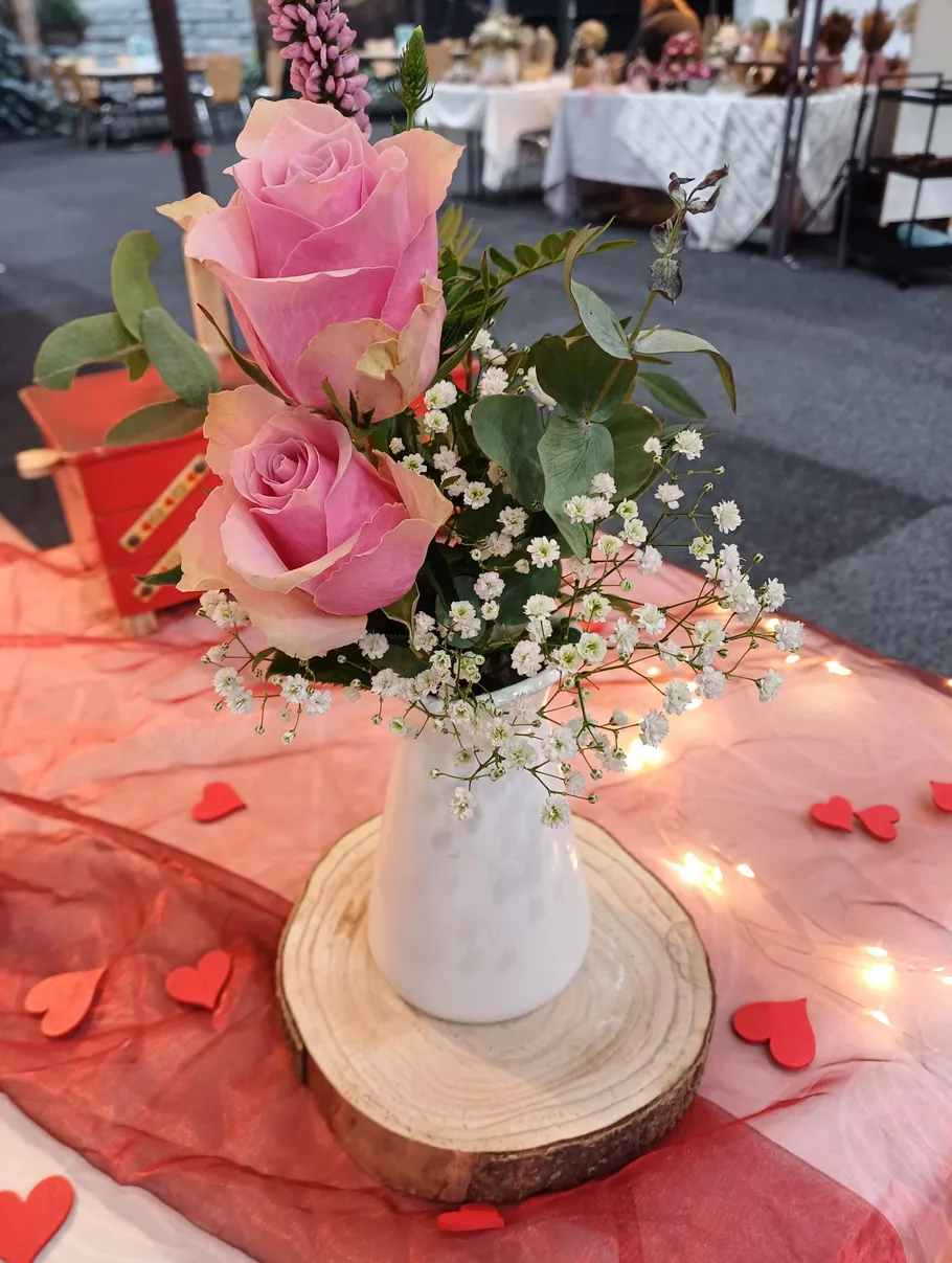 Pink roses in white vase on table.