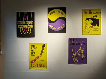 Bunte Poster mit feministischen Botschaften an Wand.