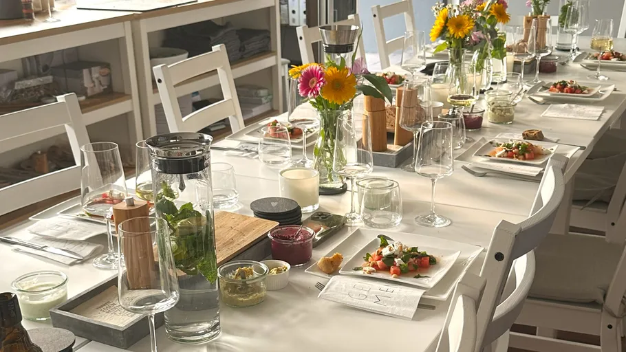 Eleganter Esstisch mit Blumen und Vorspeisen gedeckt.