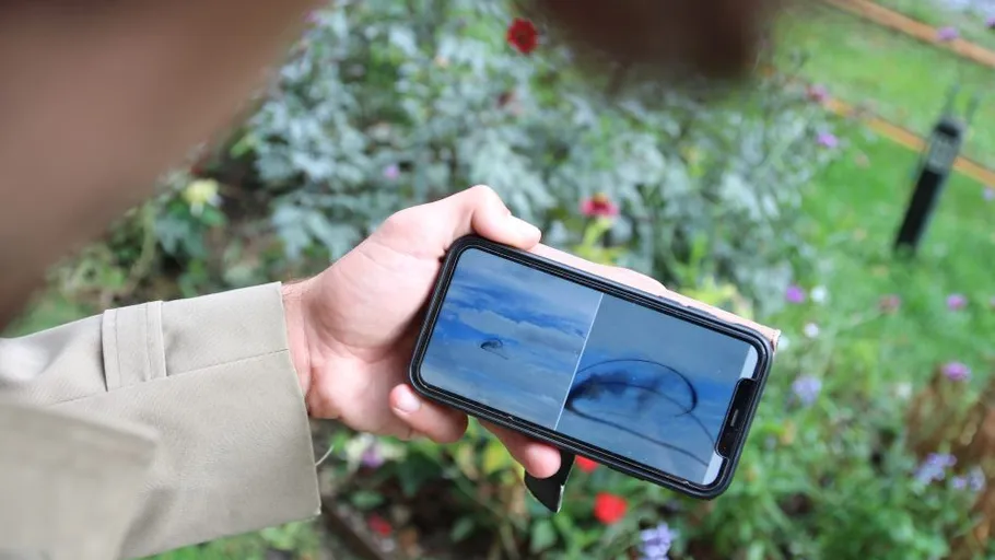 Person holding phone displaying UFO images outdoors.