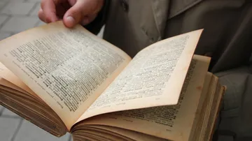 Person flipping pages of an old book.