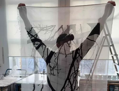Person holding translucent fabric with tree pattern.