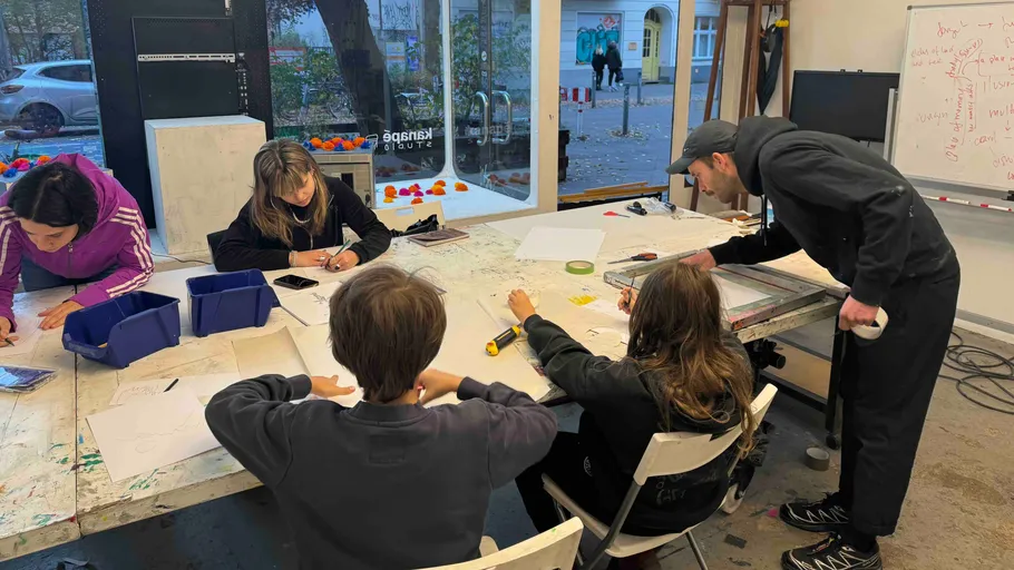 People drawing at a long table indoors.
