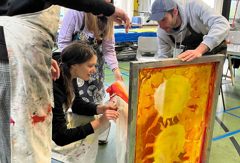 People screen printing in an art studio.
