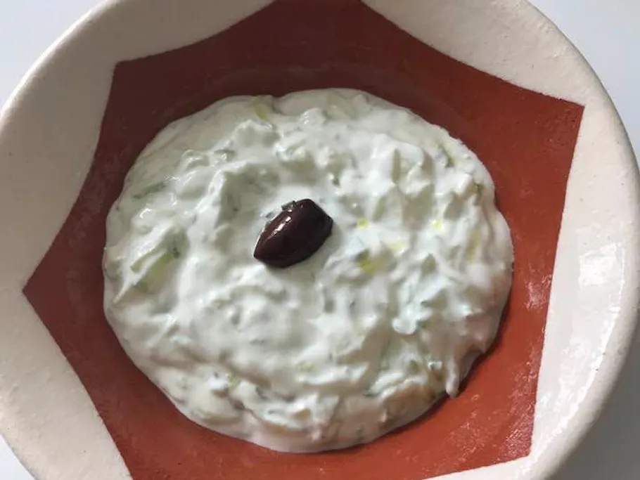 Tzatziki with olive in bowl.