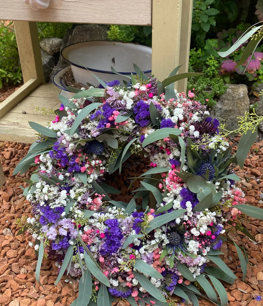 Colorful flower wreath on gravel path.