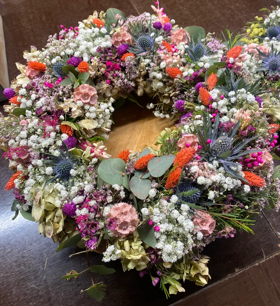 Bunter Kranz aus Trockenblumen auf Tisch.
