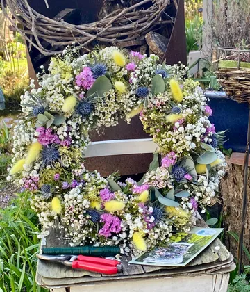 Floral wreath on rustic table outdoors.