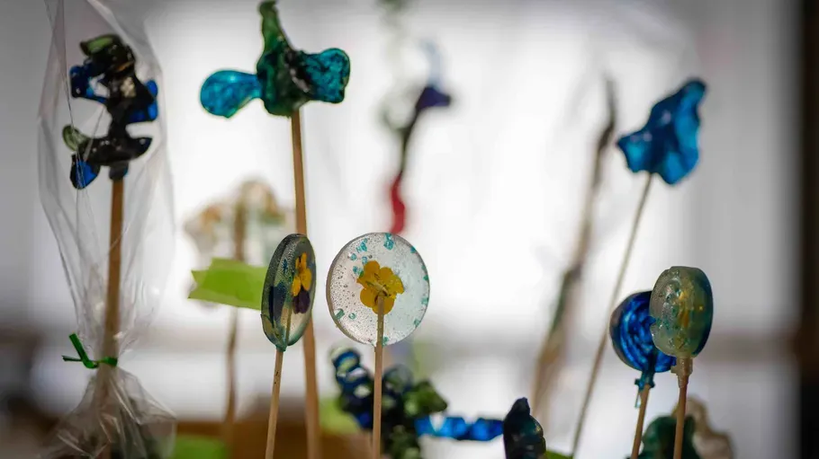 Colorful glass art on wooden sticks indoors.