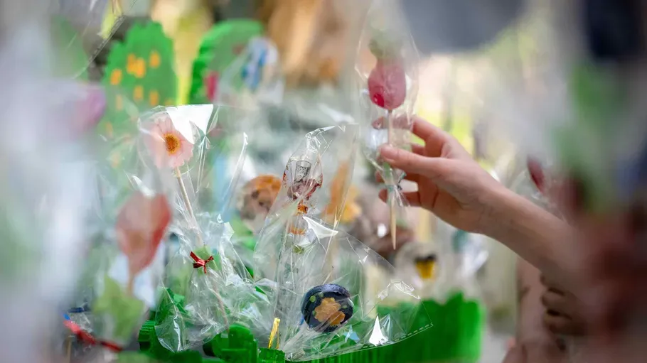 Hand choosing floral lollipops in plastic wrappers.