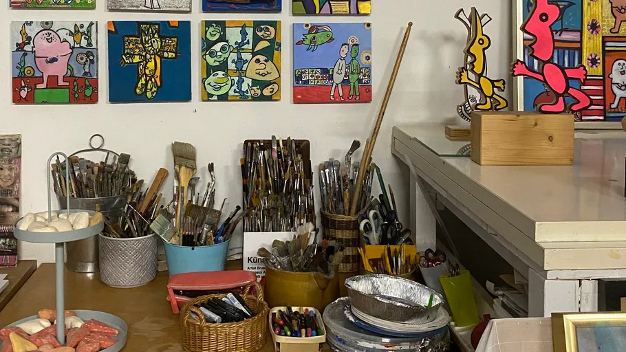 Art studio with paintings and supplies displayed.