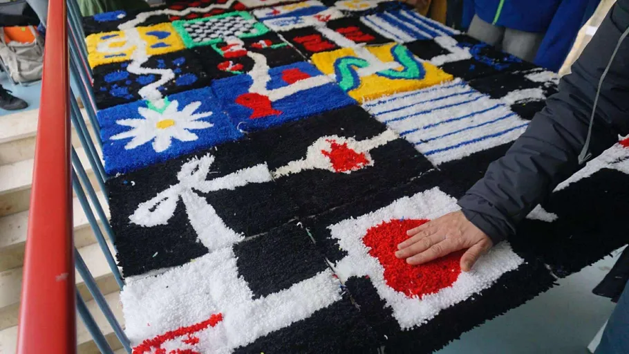 Hand berührt buntes taktiles Kunstwerk auf Tisch.