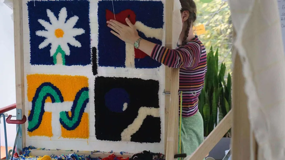 Person tufting colorful textile art pieces.