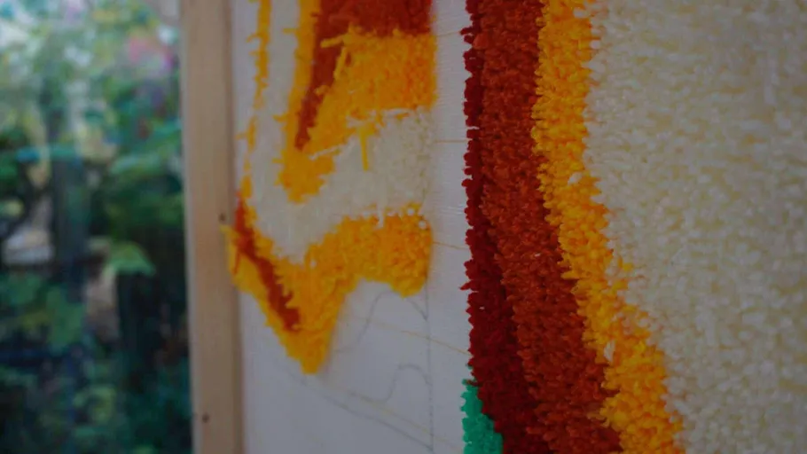 Bunte Wolle auf Leinwand, unscharfer Gartenhintergrund.