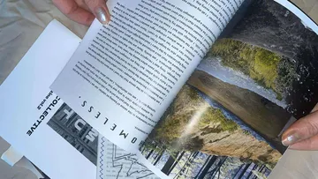 Hands turning page of a photo magazine.