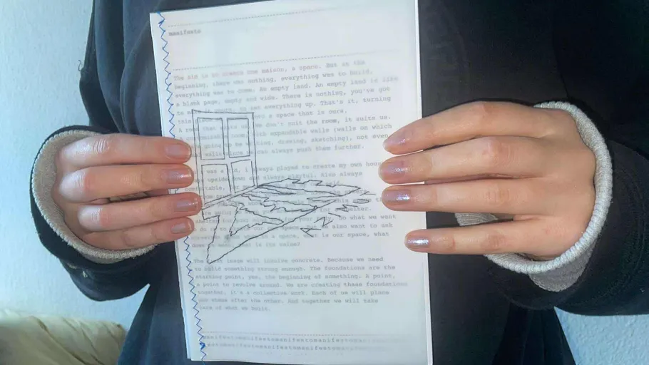Hands holding paper with typewritten text and drawing.