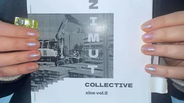 Hands holding zine with construction image.
