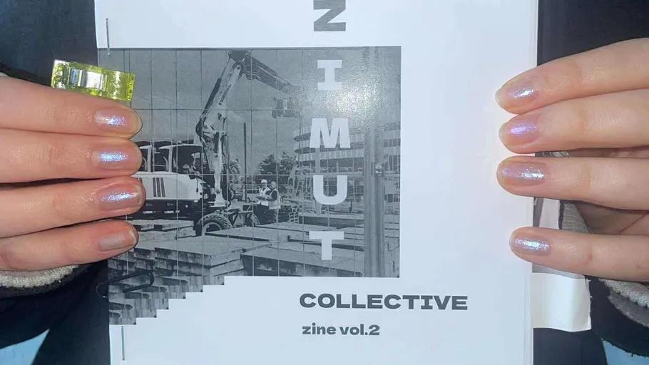 Hände halten Zine mit Bau-Bild.