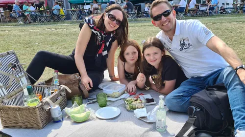 Familie macht Picknick auf Wiese mit Körben.