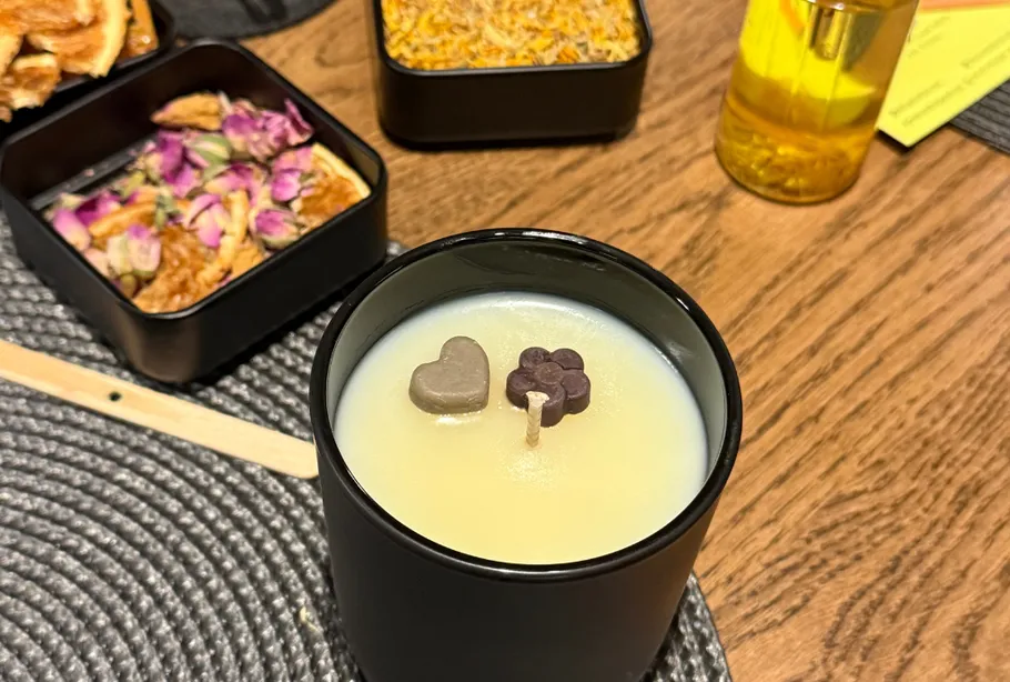Candle decorated with shapes on wooden table.