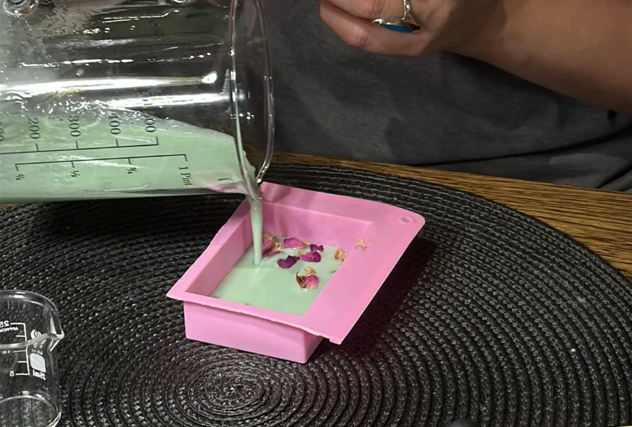 Grüne Flüssigkeit in rosa Form mit Blumen gegossen.