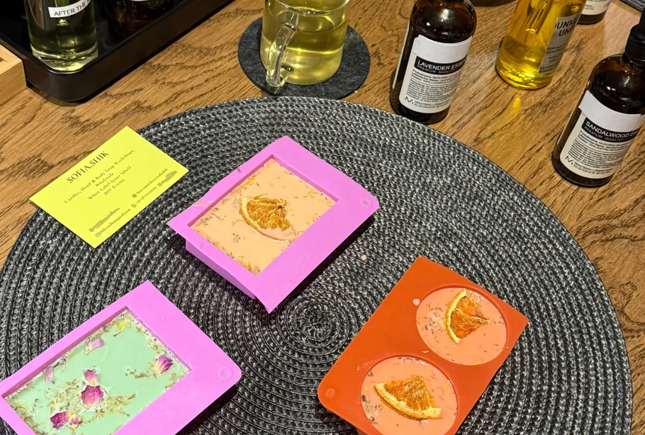 Bunte Seifenformen auf Holztisch mit Ölen.