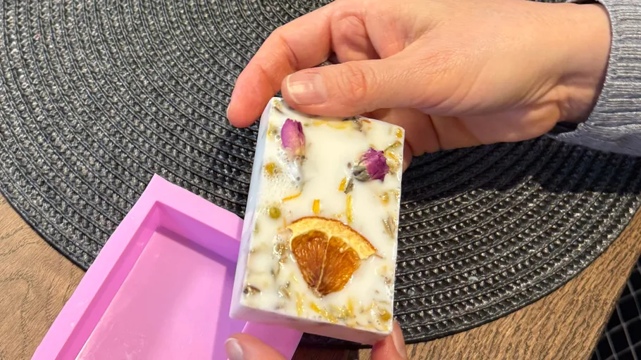 Hand hält handgemachte Seife mit Blumendekoration.