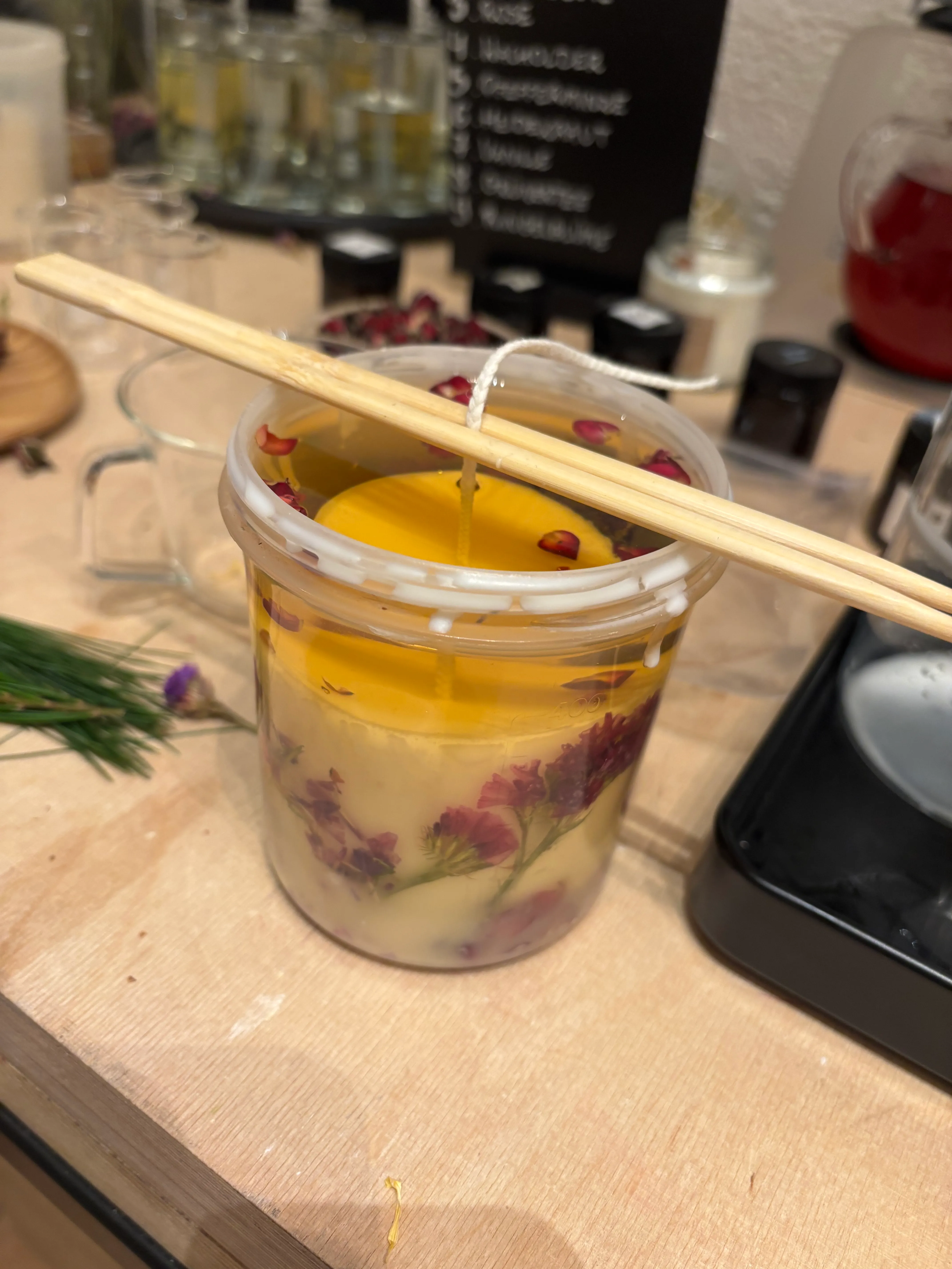 Glaskerze mit Blumen auf Tisch hergestellt.