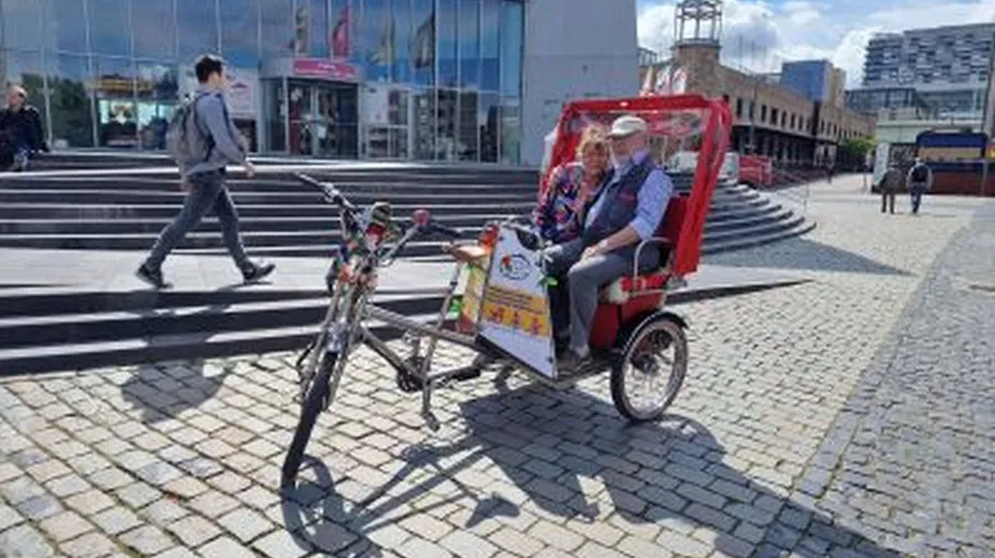Elderly couple sitting on a rickshaw outside.