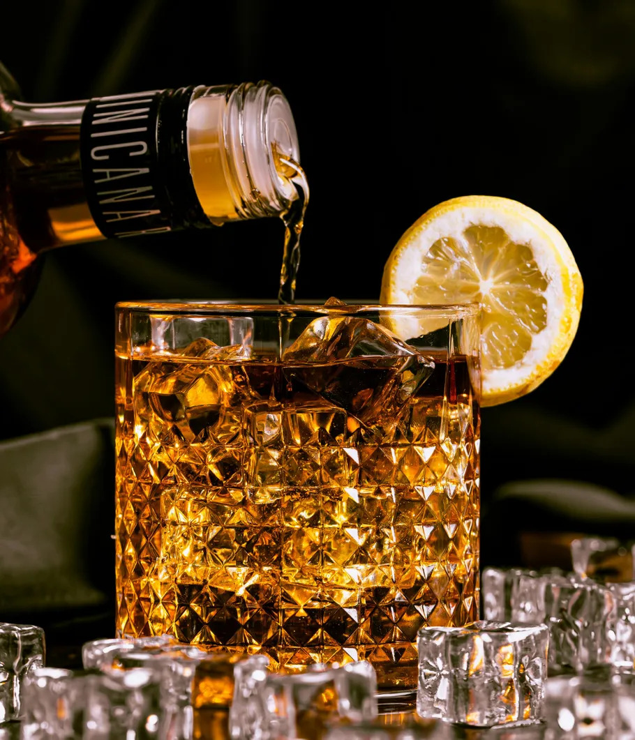 Whiskey poured into glass with lemon slice.