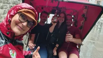 Leute im Rikscha lächeln im Regen.