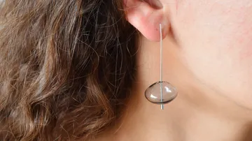 Woman wearing a unique earring indoors.