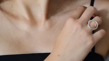 Woman wearing ring touches her neck.
