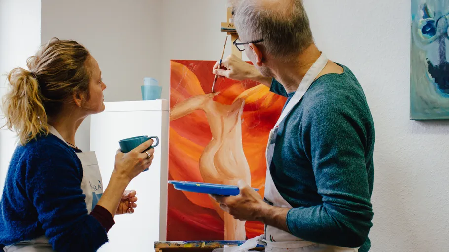 Two people painting in a bright studio.