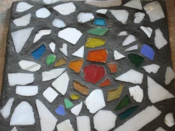 Bunte Mosaikstücke sind in grauem Hintergrund eingearbeitet.
