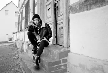 Person sitting on steps, wearing a coat.