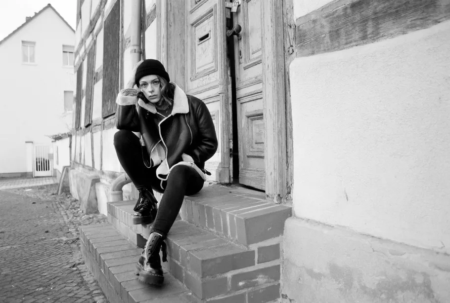 Person sitting on steps, wearing a coat.