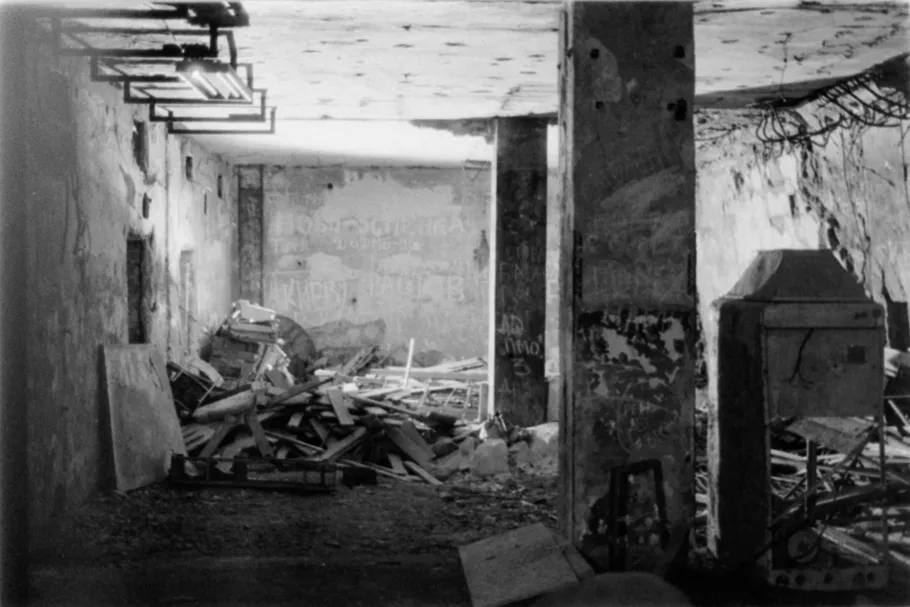 Ruined room with debris and old graffiti.
