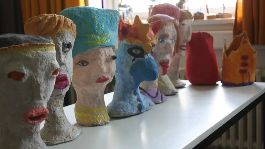 Colorful papier-mâché heads displayed on a table.
