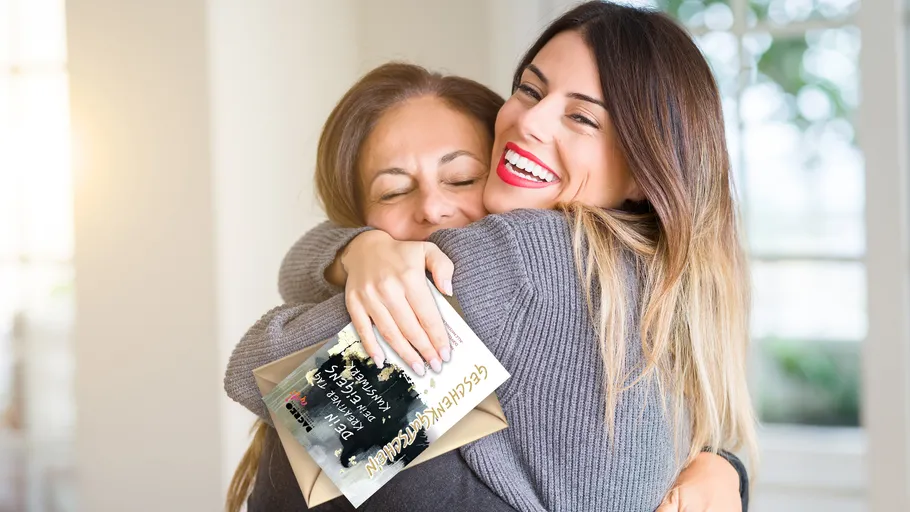 Zwei Frauen umarmen sich freudig drinnen.