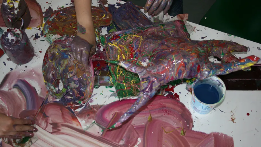 Bunte Hände malen auf Tisch, abstraktes Chaos.