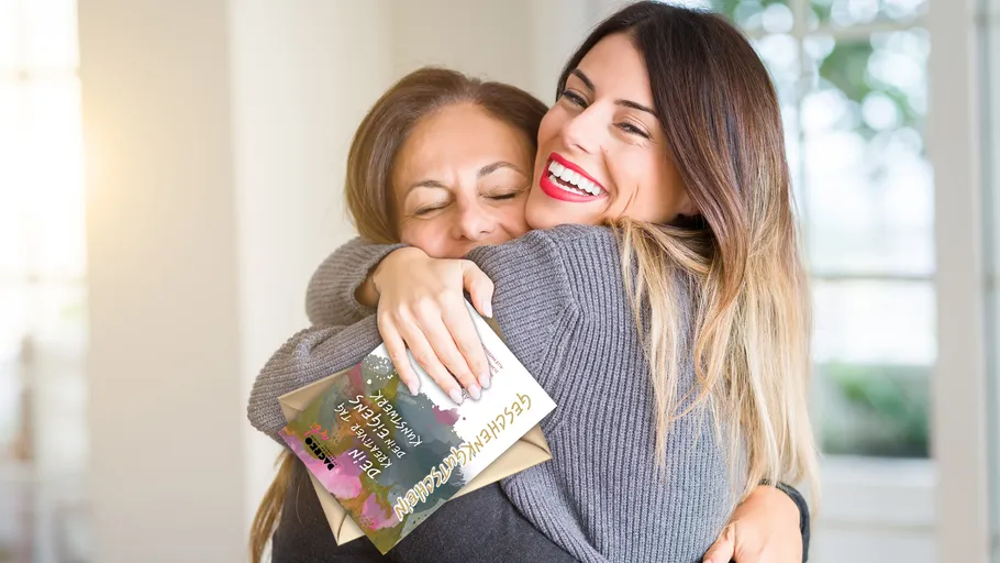 Two women hugging inside, one smiling.